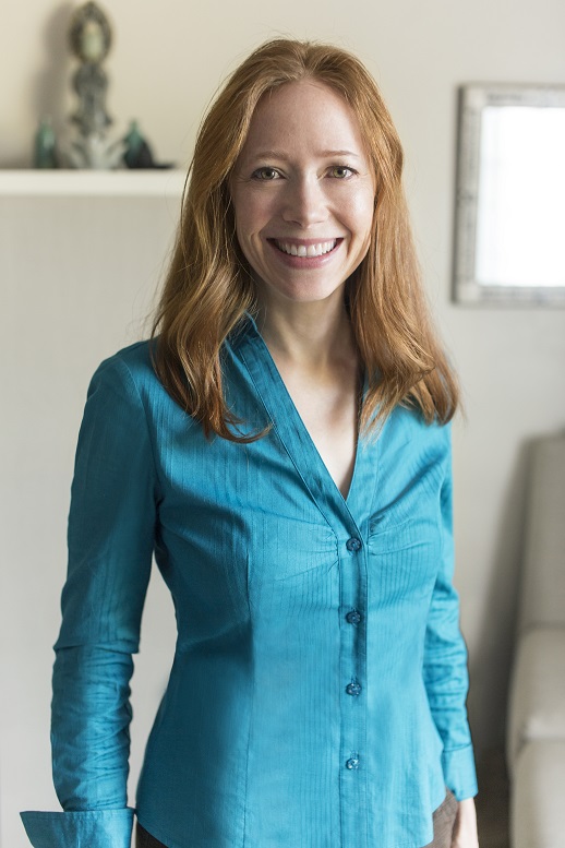 Caucasian female with red hair in teal button up dress shirt with smiling face