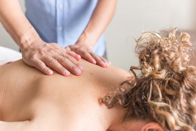 Traditional Asian Medicine massage with male therapist applying both hands in healing to the back of female patient on table