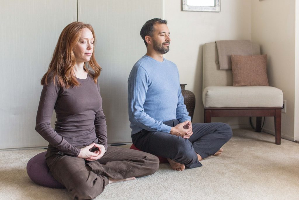 Caucasian female and male both sitting in lotus meditation pose meditating