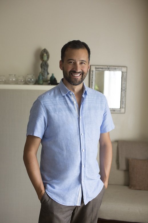 Caucasian male with black hair in light blue short sleeved button up shirt and khaki pants with smiling face