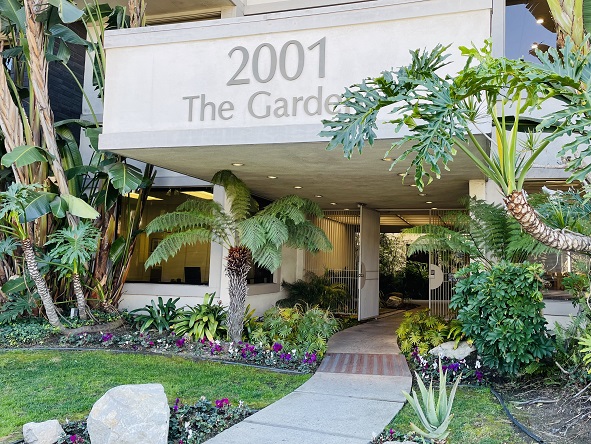 Healthy Qi of Los Angeles West LA office building location with sidewalk leading to main door featuring green grass and a garden with purple, white and pink flowers and trees